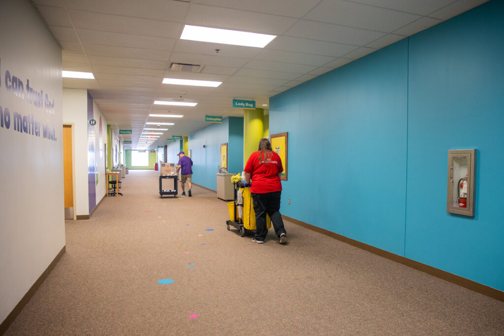 staff member at church pushing custodial cart