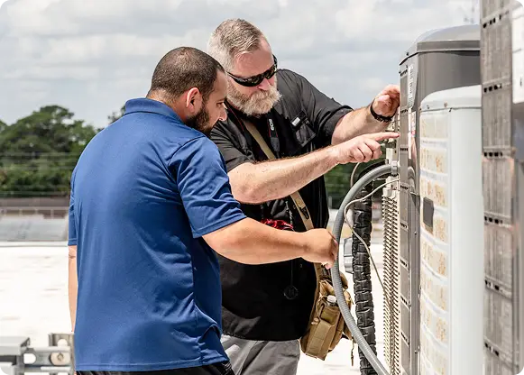 Technicians servicing a rooftop HVAC unit